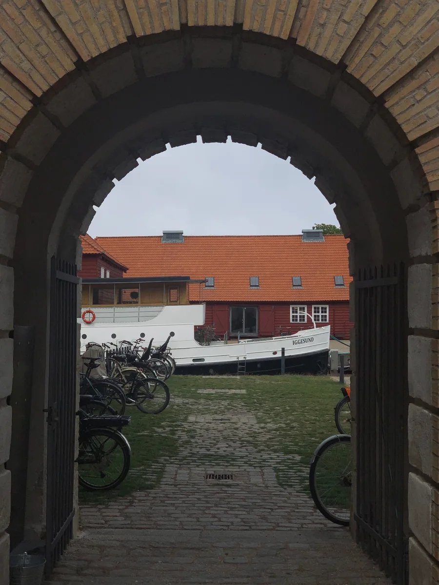 A stone archway framing bicycles and a boat
