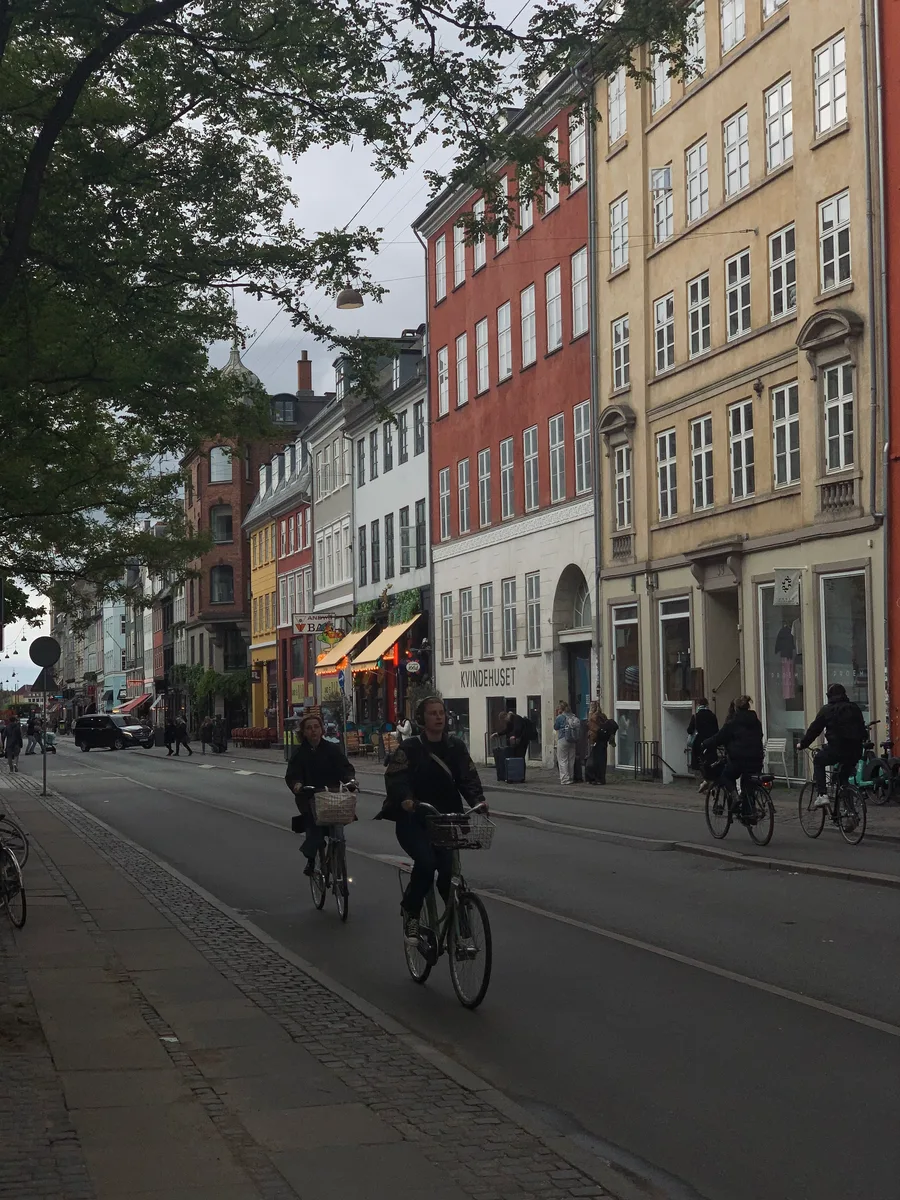 Cyclists riding past colorful buildings on a Copenhagen street