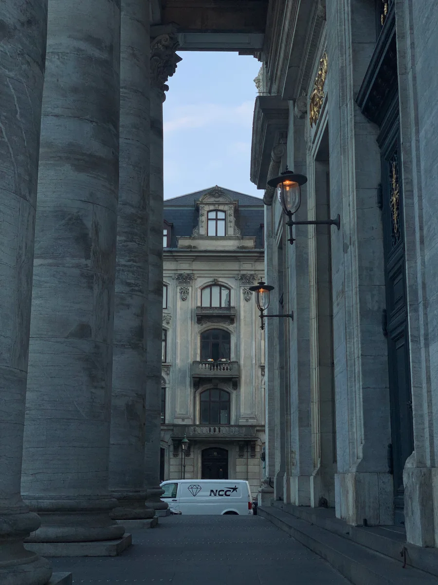 A passage between stone columns framing a city building