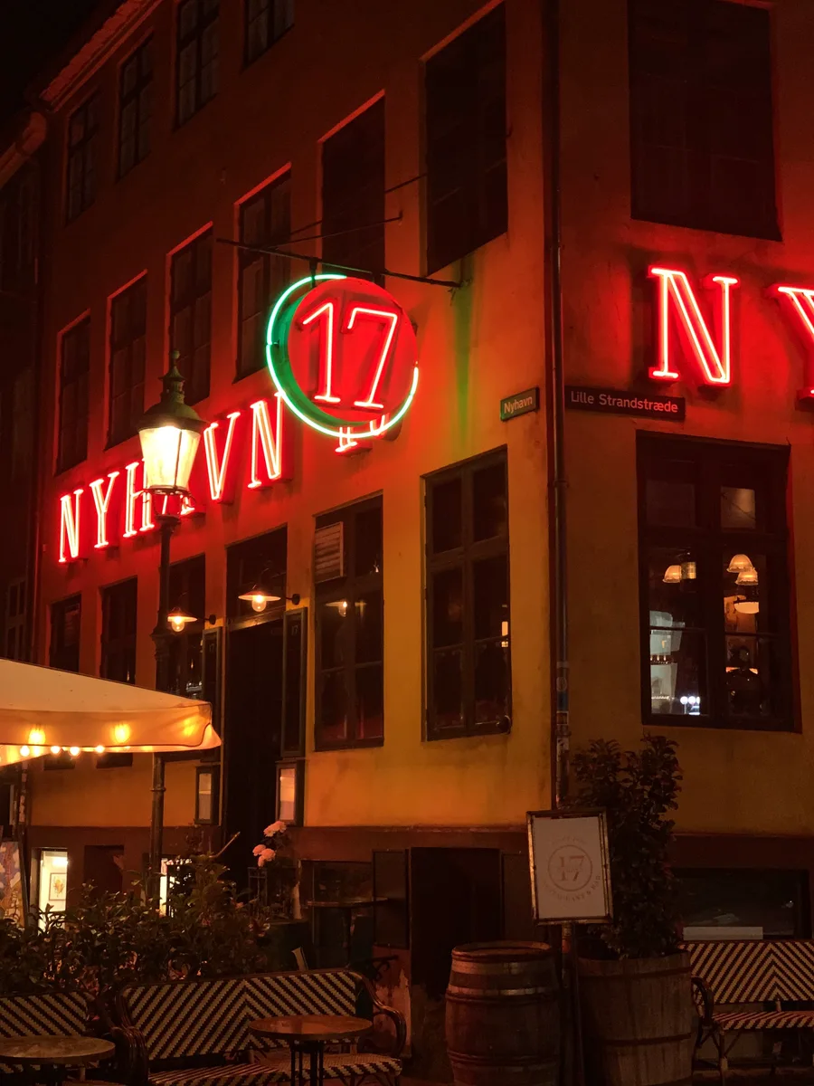 Red neon restaurant signs glowing above sidewalk tables