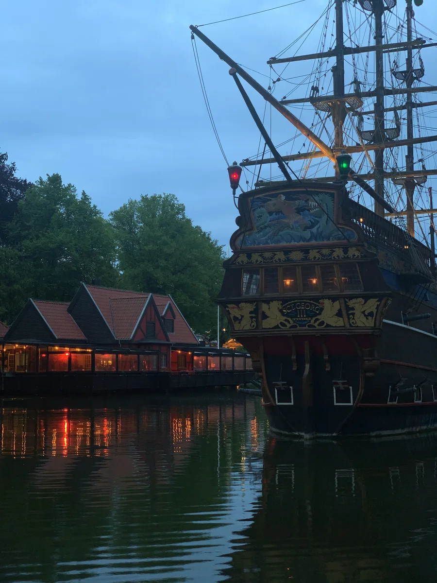 A sailing ship reflected in a garden lake at dusk