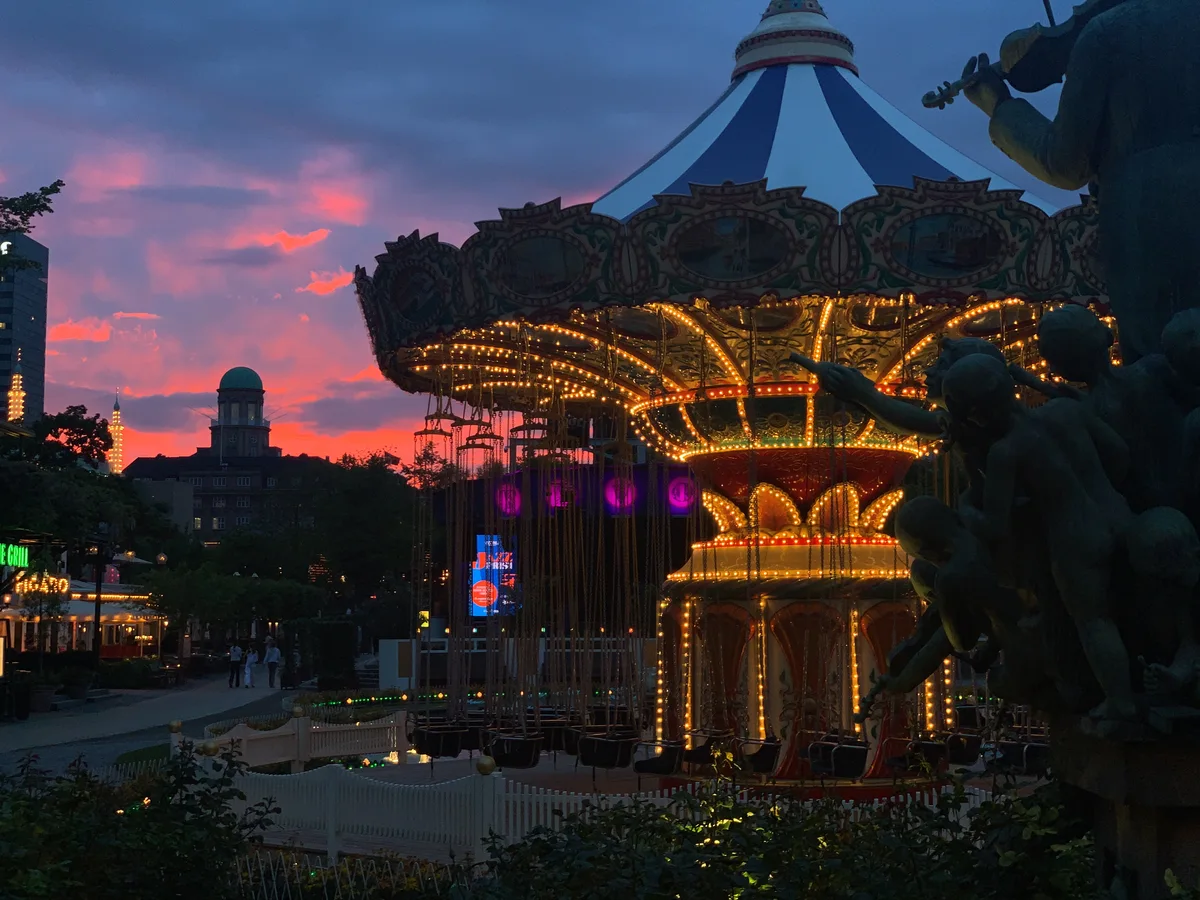An illuminated carousel beneath a vivid pink evening sky
