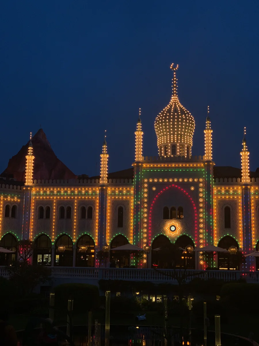 An ornate illuminated building reflected in dark water