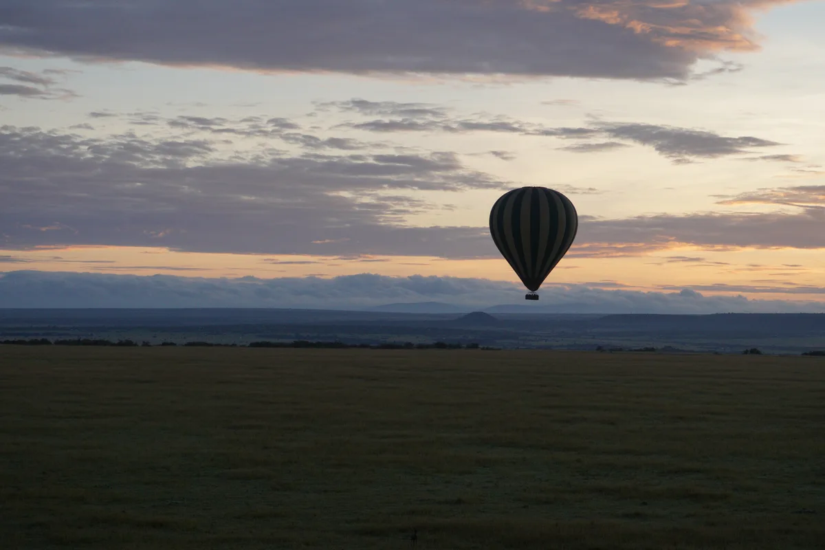 A hot-air balloon silhouetted against a pastel sunrise