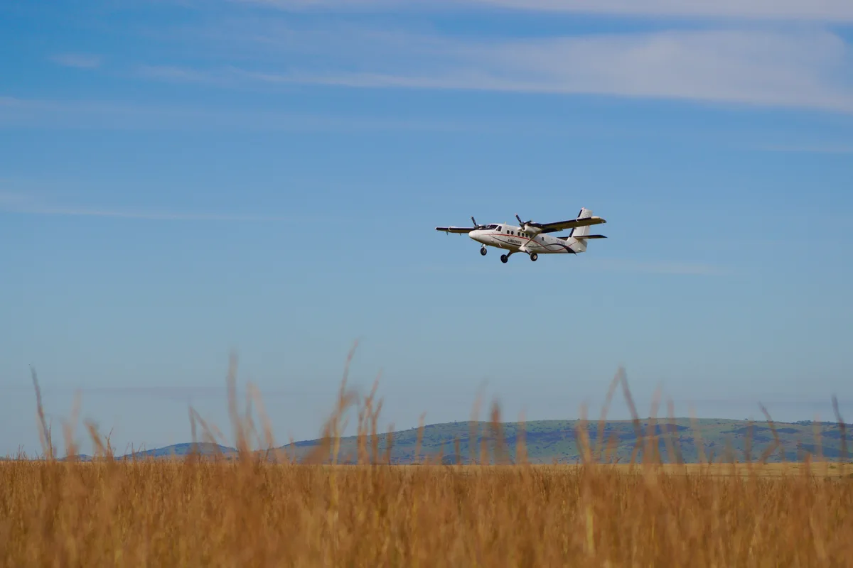 A small propeller plane flying low over the grassland