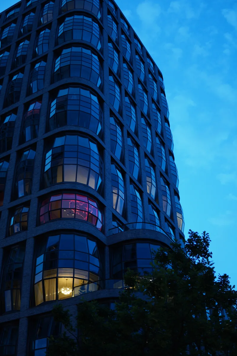 A curved glass building at blue hour