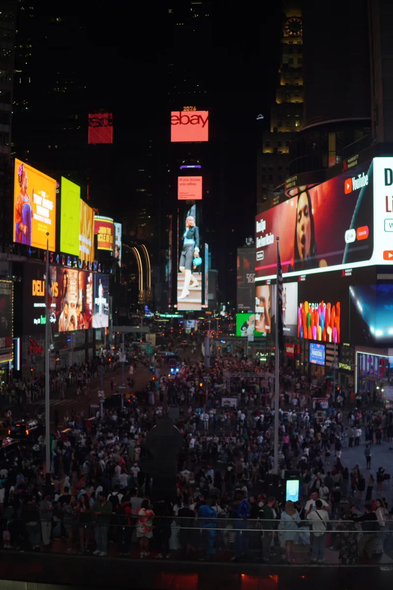 Crowds beneath illuminated billboards in Times Square at night