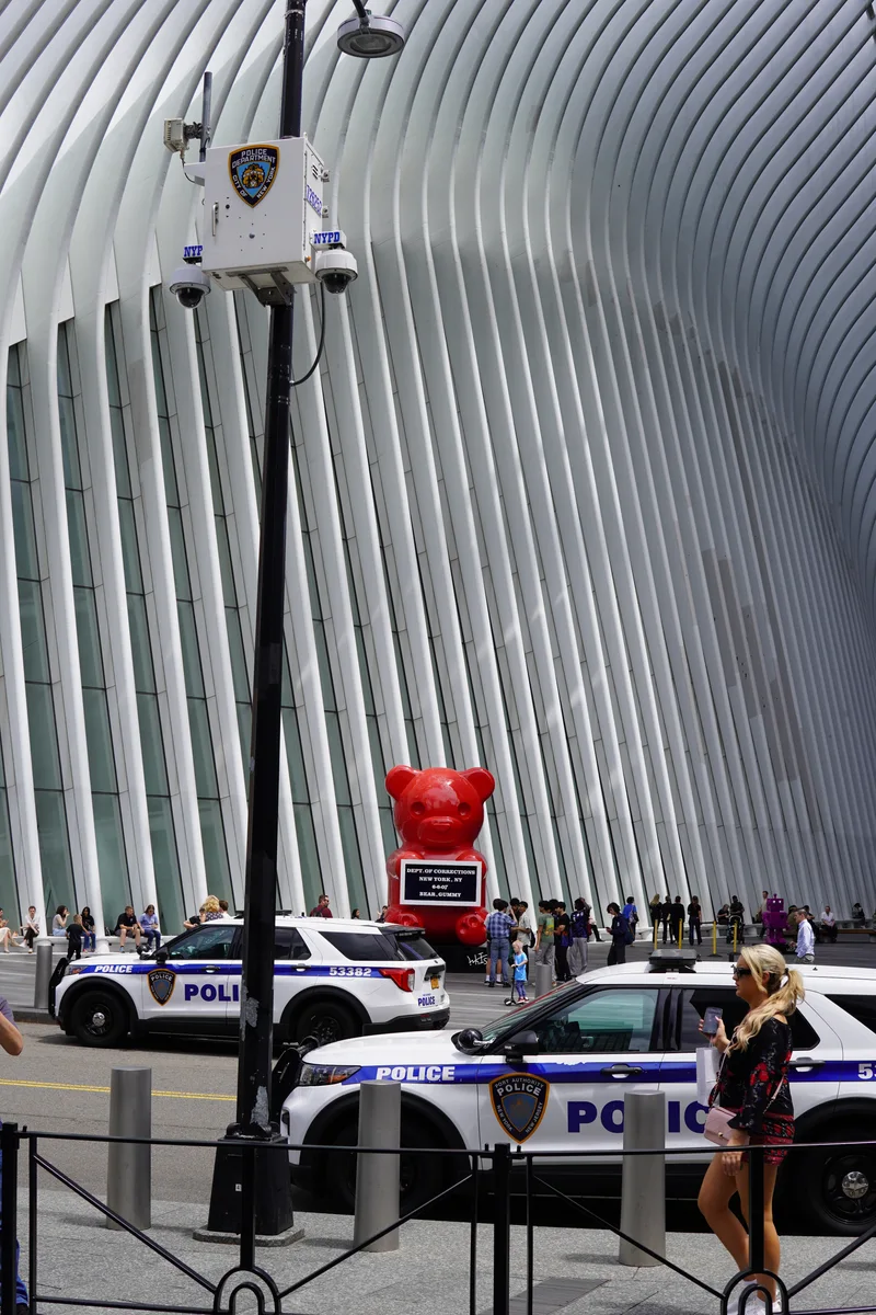 A red gummy bear sculpture beneath the white ribs of the Oculus