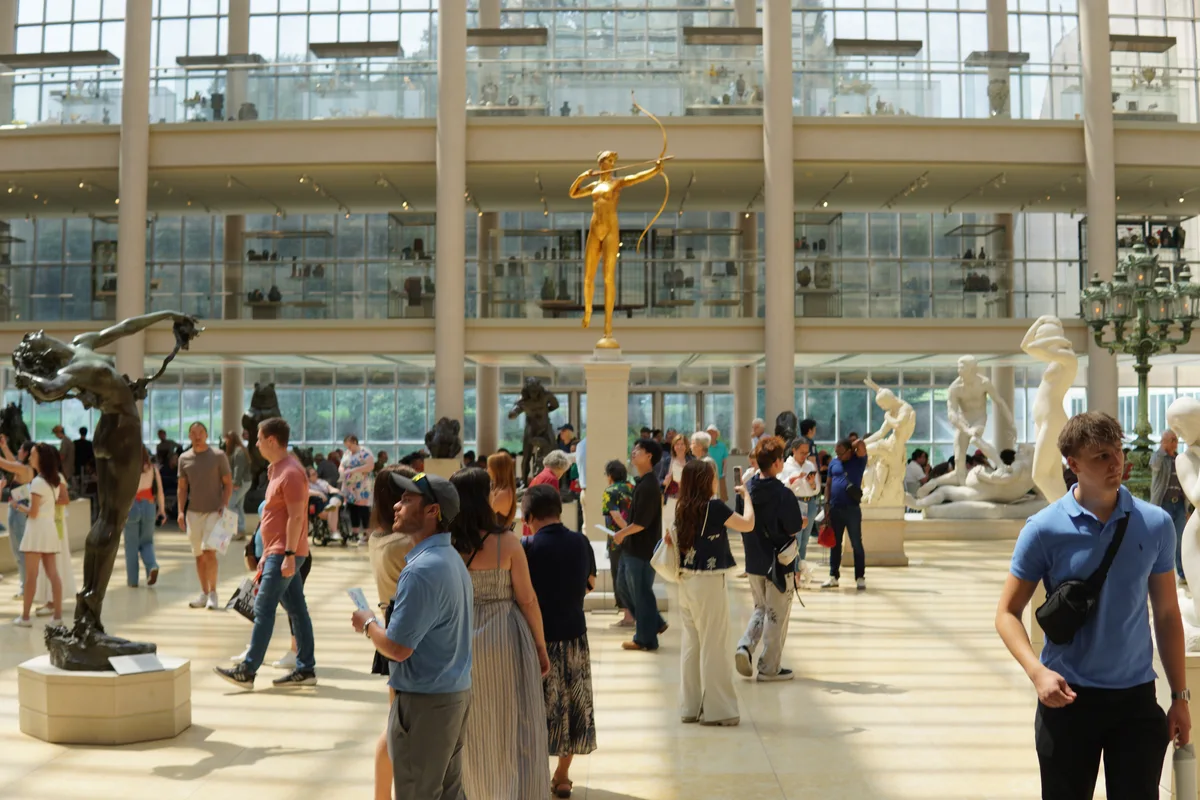 Visitors in a bright museum hall around a golden sculpture