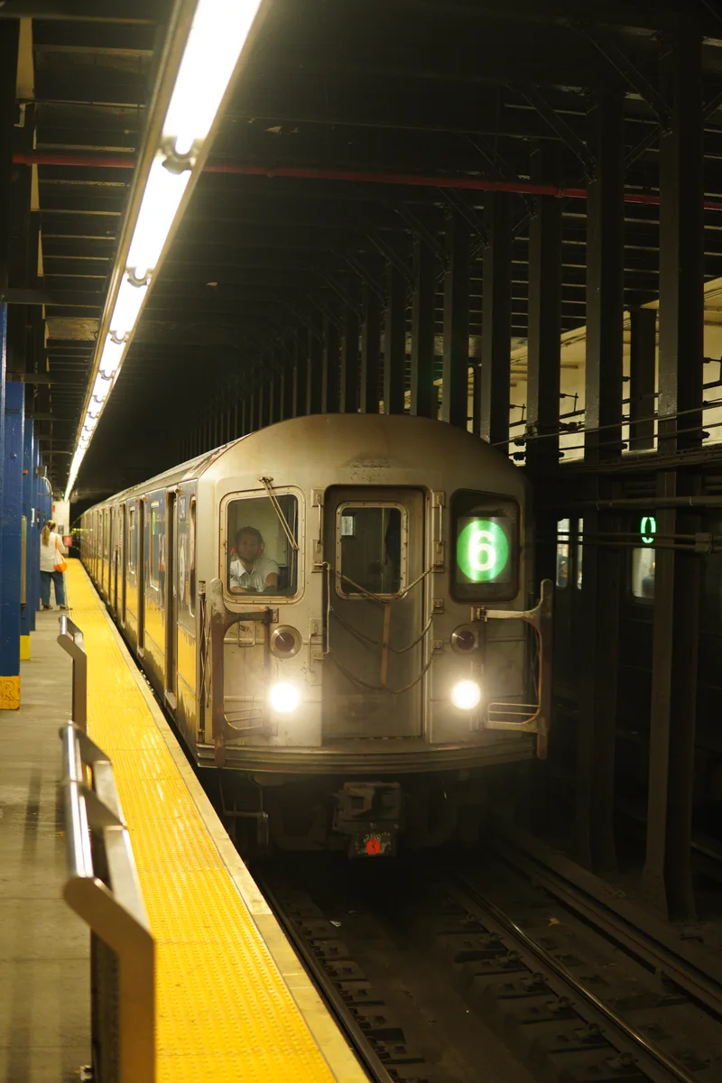 A subway train arriving beside a yellow-edged platform