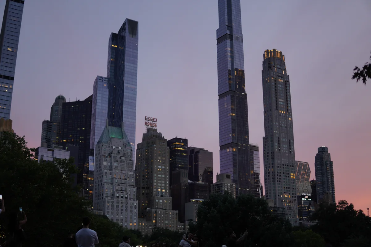 Slender skyscrapers rising beyond Central Park at sunset